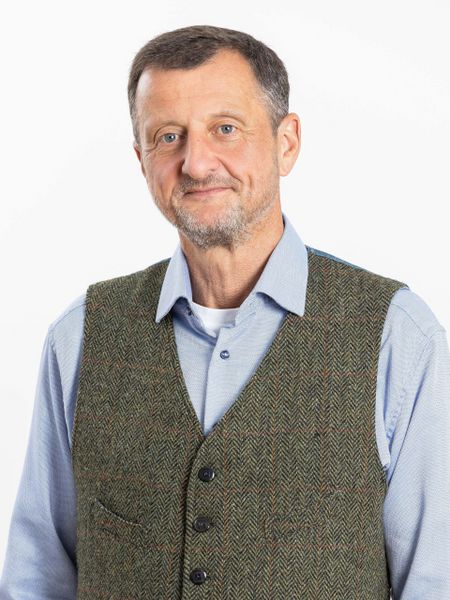 Portrait ISPA Vorstand Georg Chytil blickt freundlich mit geschlossenem Mund in die Kamera. Er trägt ein blaues Hemd unter einem grau-melierten Gilet.