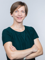 Katharina Schell Portrait Katharina Schell, freundlich lächelnd, mit vor der Brust verschränkten Armen