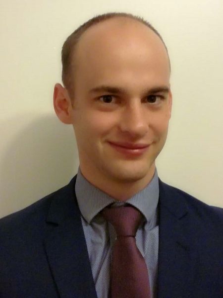 <p>Jürgen Bauer</p> Portrait von Jürgen Bauer, der mit geschlossenem Mund lächelt. Er trägt einen dunklen Anzug und eine rote Krawatte.