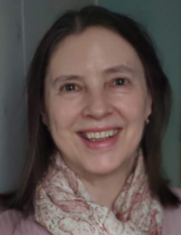 Margareth Antonescu Margareth Antonescu trägt ein blass-rosa Oberteil und einen rosa-weiß-geblümten Schal, sie lächelt mit geöffnetem Mund