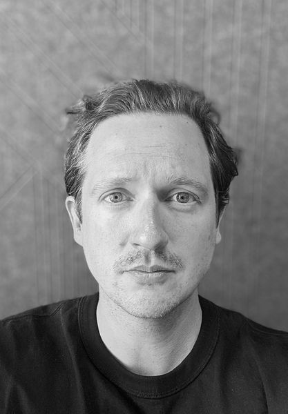 Ein schwarz-wei&szlig;-Portraitfoto von Thomas Spieler, der direkt in die Kamera sieht.