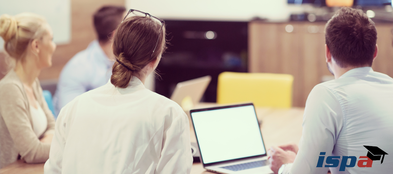 vier Personen von hinten, die einem Vortrag zuh&ouml;ren; helles Bild, rechts unten das ISPA Academy Logo