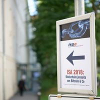 ISA 2018: Blockchain jenseits von Bitcoin & Co. Das Bild zeigt einen Wegweiser, der mit einem rechten Pfeil auf den Eingang des Veranstaltungsgeb&auml;udes zeigt.