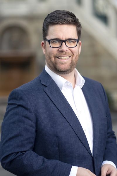 Ein Portrait von Mag. Stefan Ebenberger, dem Generalsekret&auml;r der ISPA. Man sieht einen Mann in seinen fr&uuml;hen 40ern mit 5-Tage-Bart und schwarz gerahmter Brille, Kurzhaarfrisur und in einem blauen Anzug, der in die Kamera l&auml;chelt.