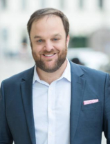 Portrait Michael Hirschbrich, freundlich l&auml;chelnd, im Anzug ohne Krawatte